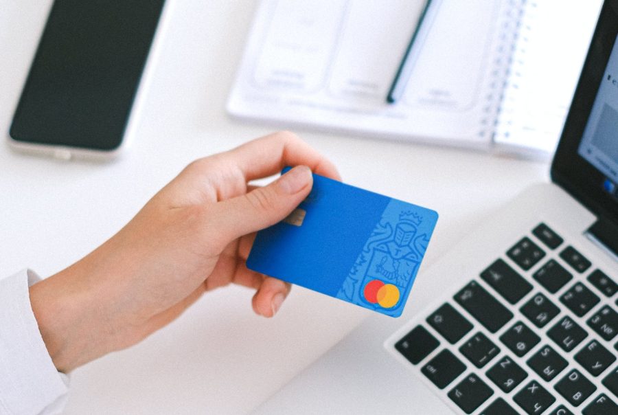 Hand houdt een bankkaart naast een laptop: online betaling van de voorschotfactuur