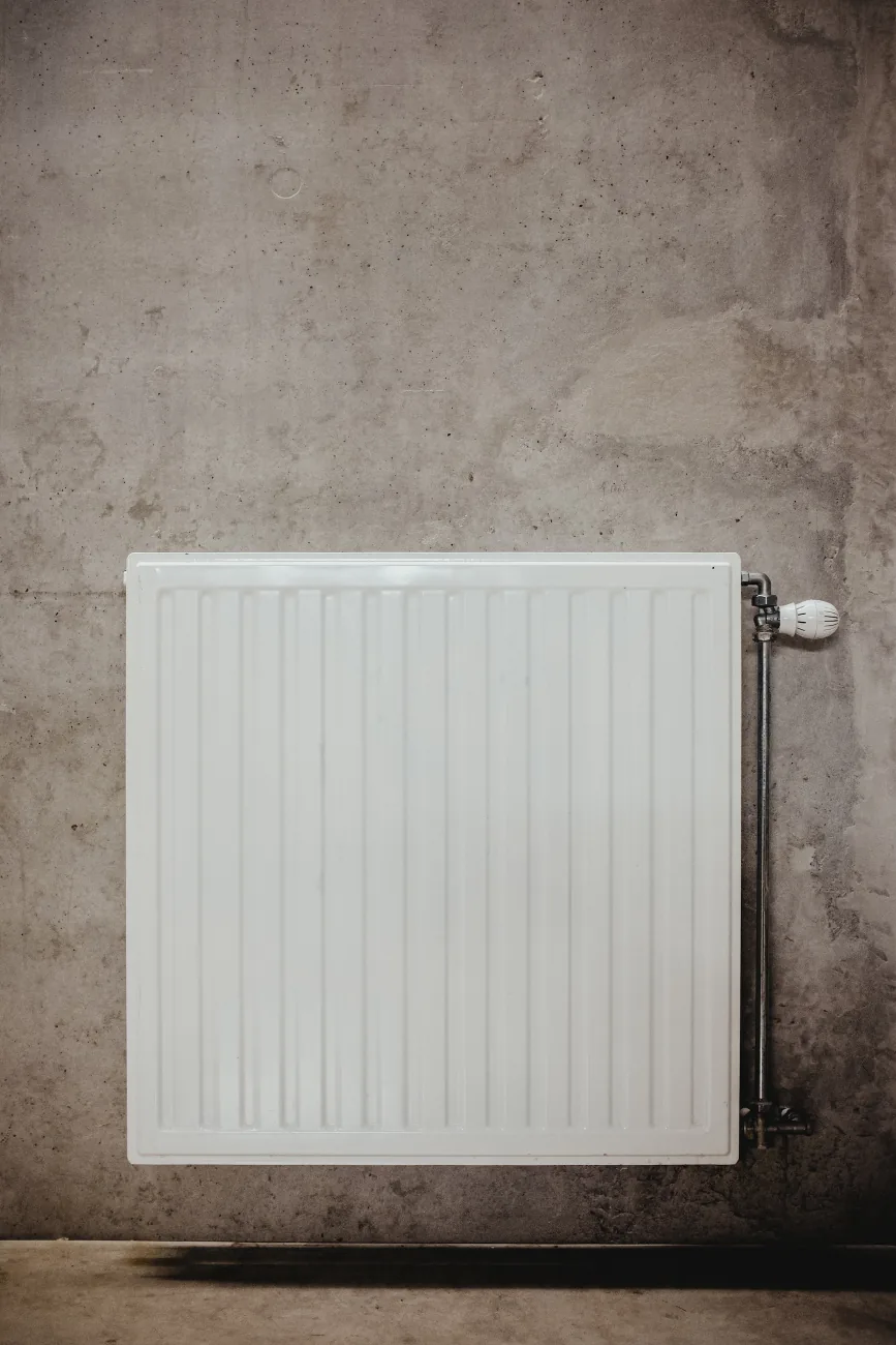 Witte radiator tegen een kale betonnen muur