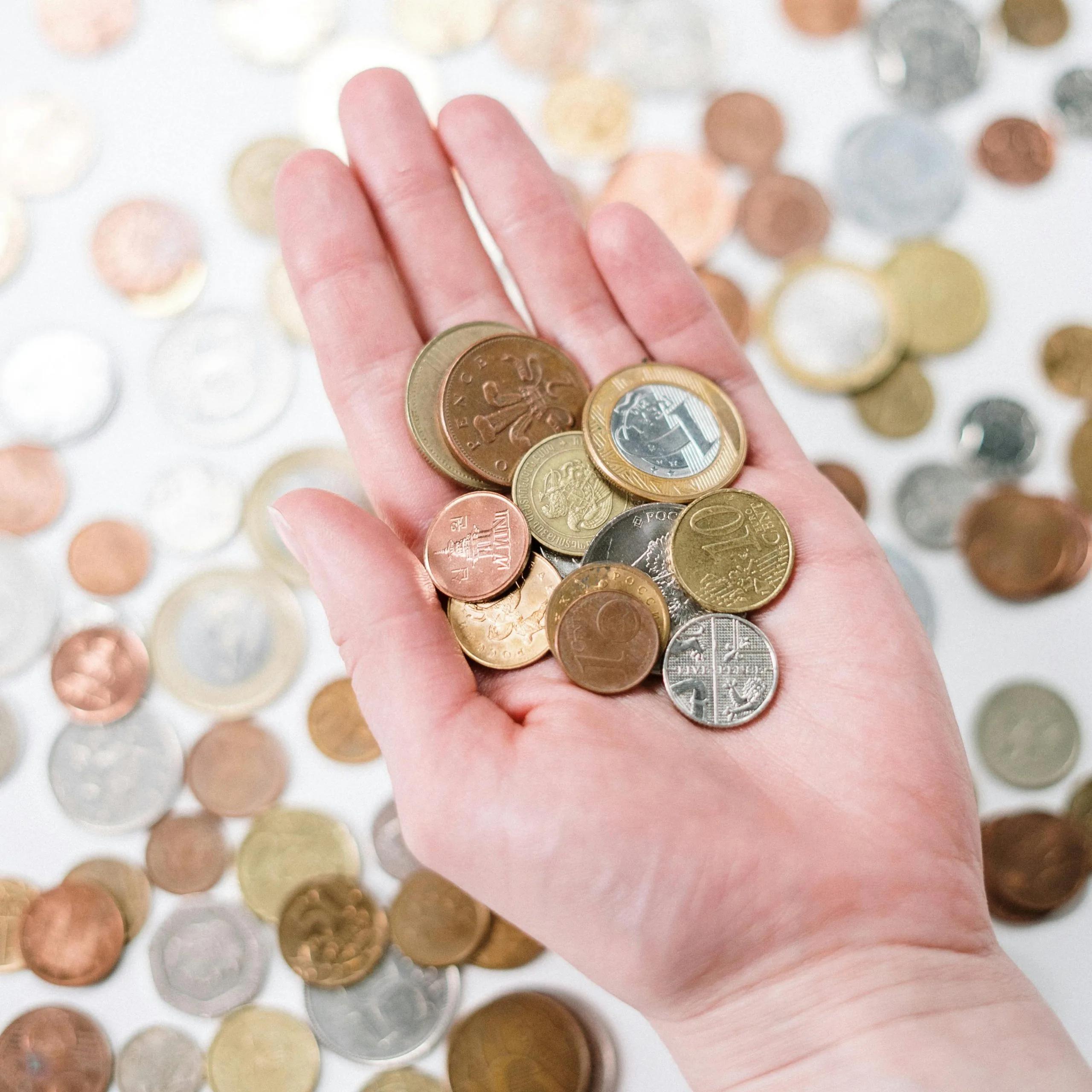 Hand vol euromunten boven een tafel bezaaid met kleingeld