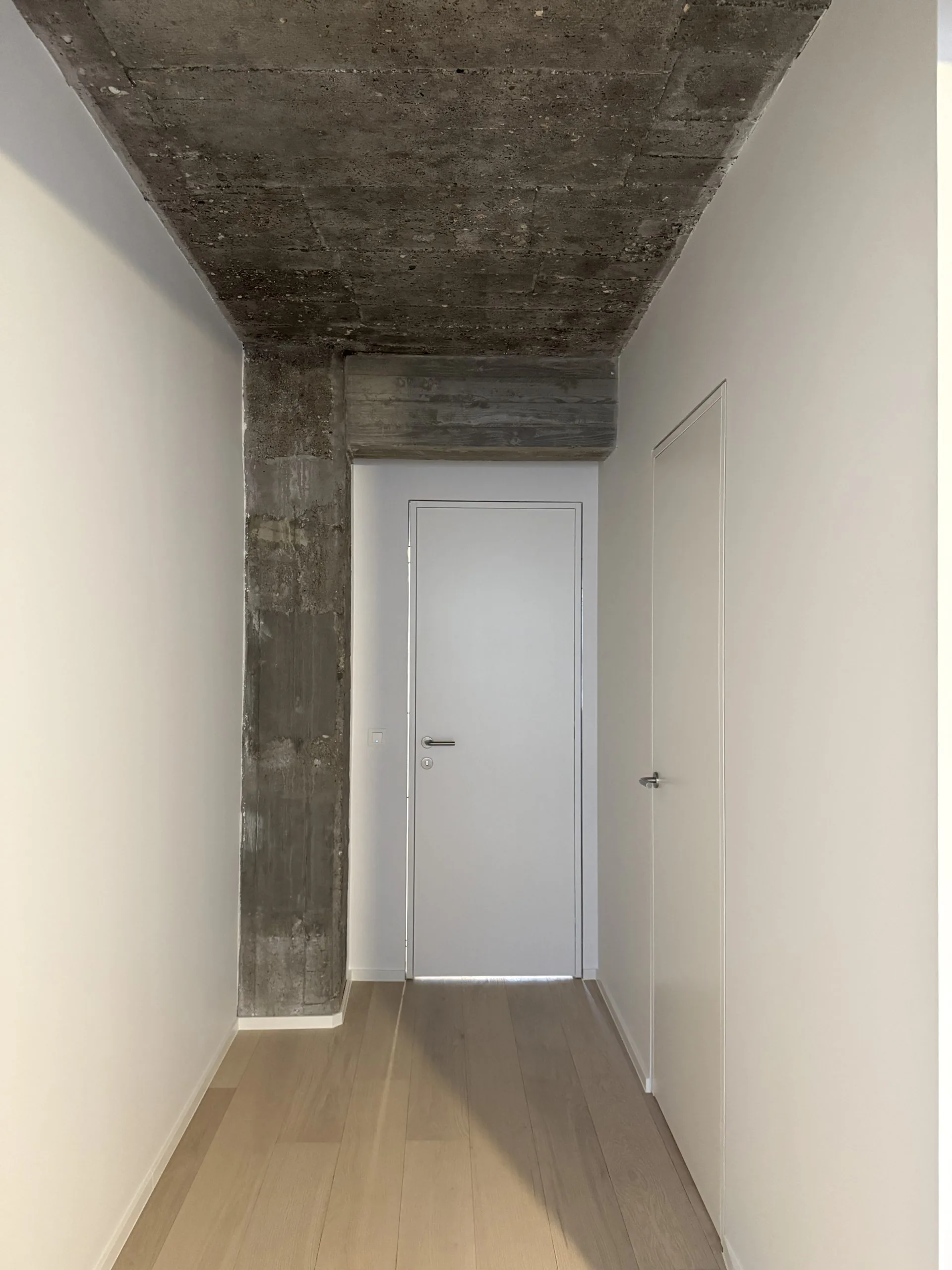 Gang met wit geschilderde muren onder een ruw betonnen plafond, project Nova I