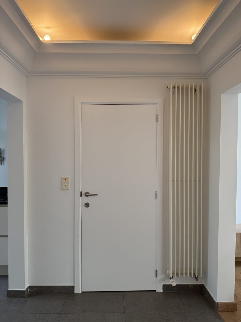 IMG_0267 Wit geschilderde hal met deur, radiator en verlichte plafondkoof, project Pure Matter