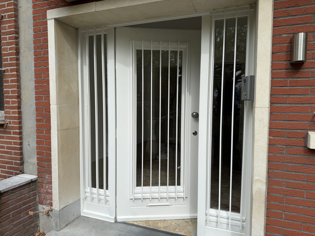 Witte voordeur met zijlichten en spijlen in een bakstenen gevel, project Iron Whisper