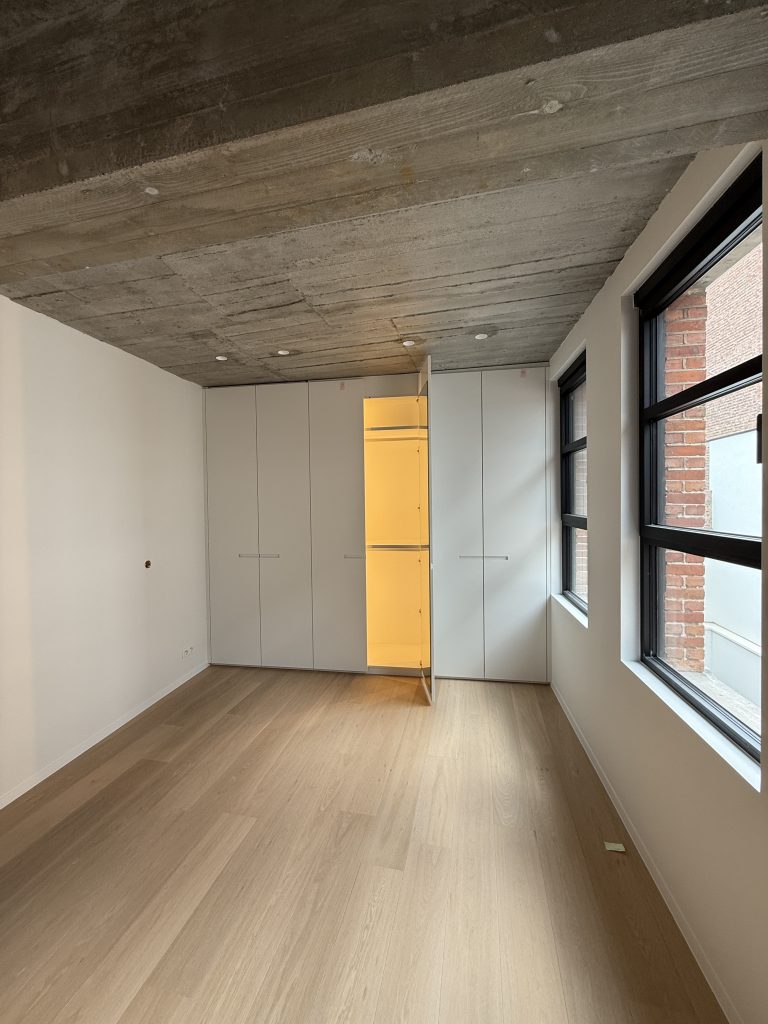 Appartement met betonnen plafond, wit geschilderde wanden en gele deur, project Nova II